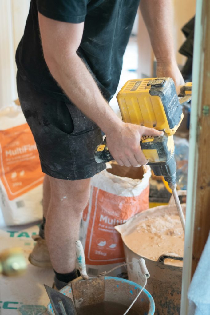 man with drill mixing a bucket of plaster